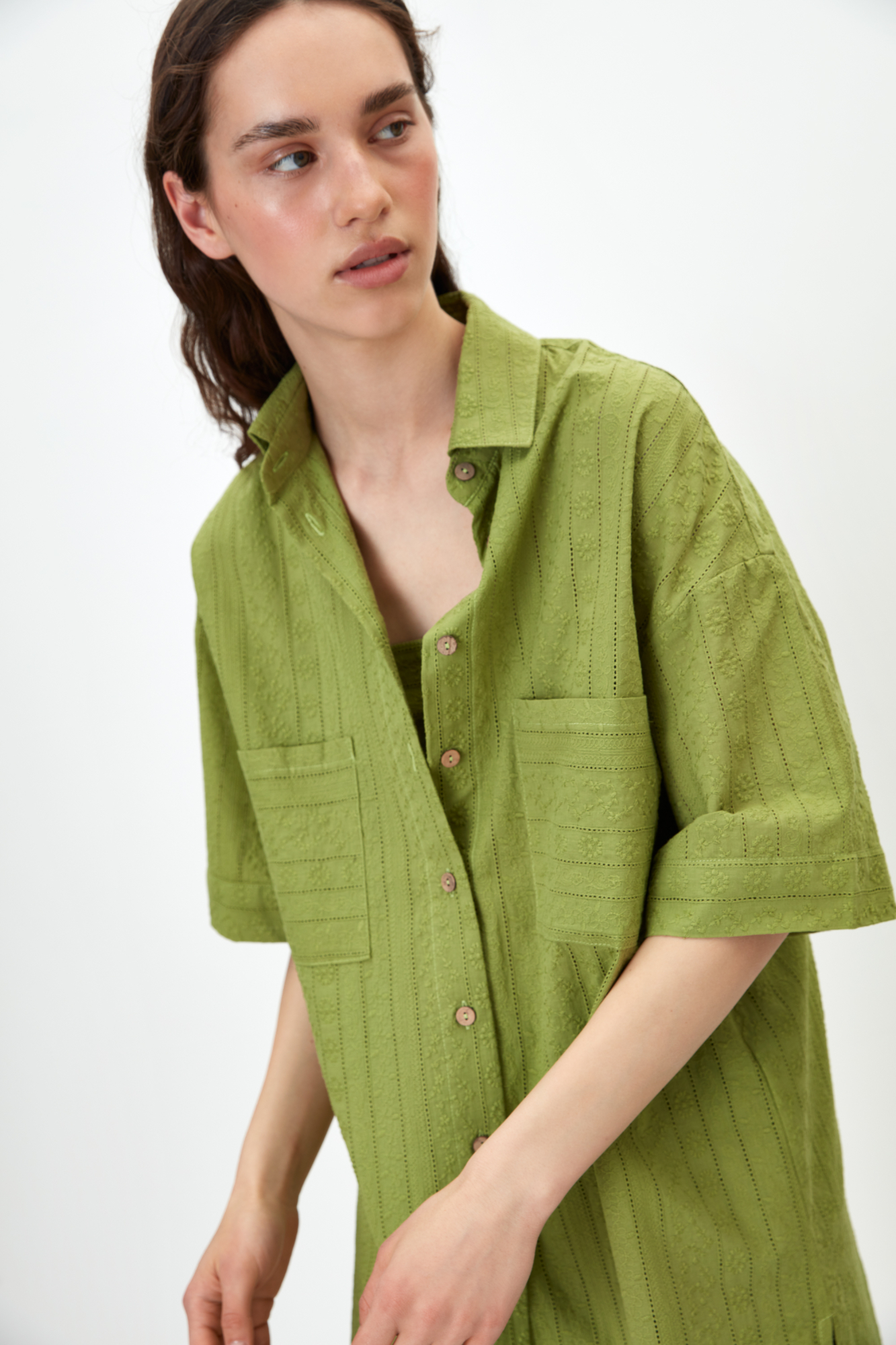 Рубашка из 100% хлопка. Модель прямого кроя, с отложным воротником и короткими рукавами. Застёгивается на пуговицы по всей длине. На груди расположены два накладных кармана. Ткань имеет текстурированную поверхность с вертикальными полосами и вышитым узором.<br />
