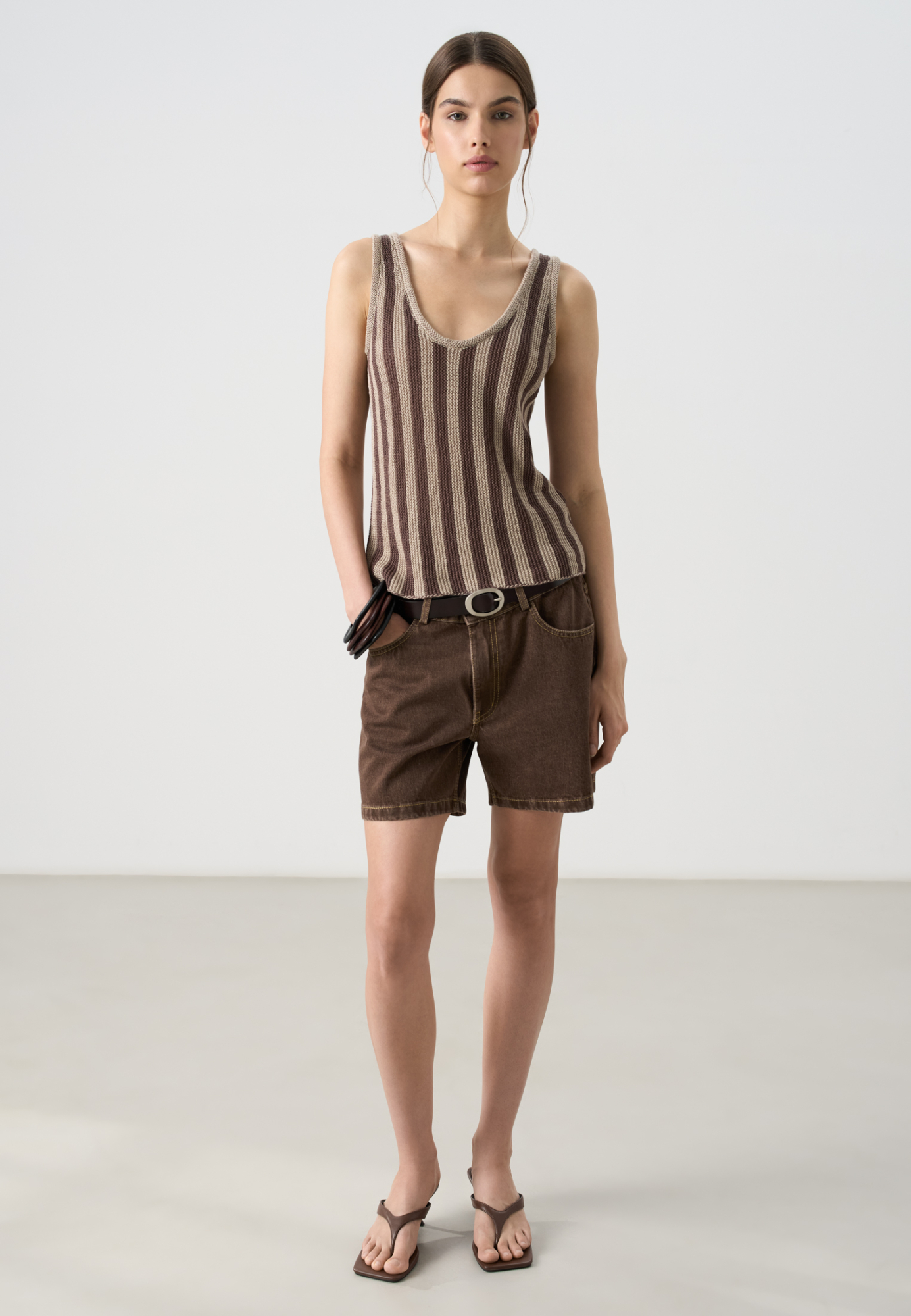 Трикотажная майка из 100% льна. Модель на широких бретелях, с глубокой проймой, U-образным вырезом горловины и валиком по низу. Изделие выполнено в вертикальную полоску.