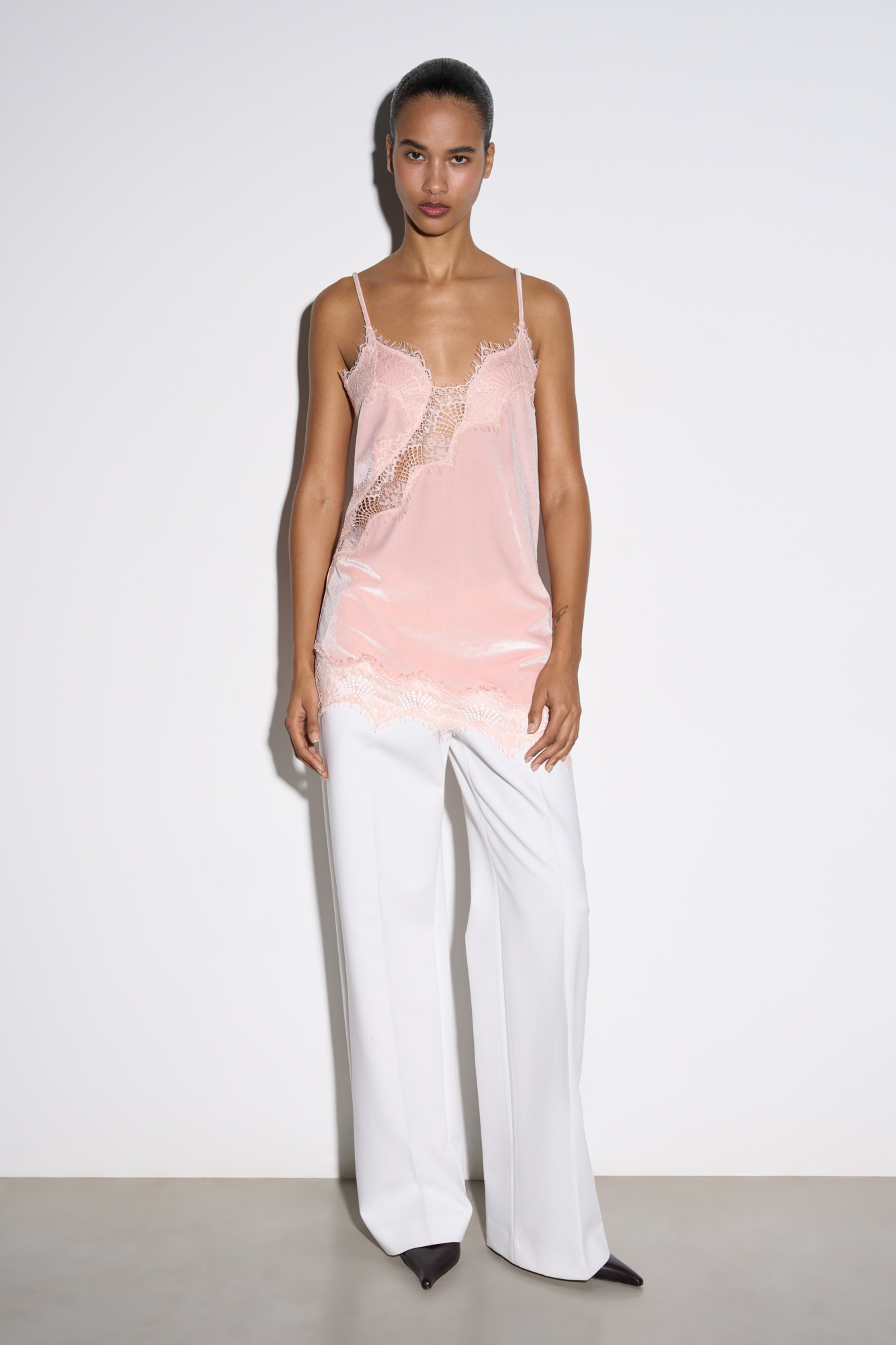 Топ из бархатной вискозы, декорированный тонким кружевом. Модель асимметричного кроя, с глубоким вырезом декольте на тонких бретельках.