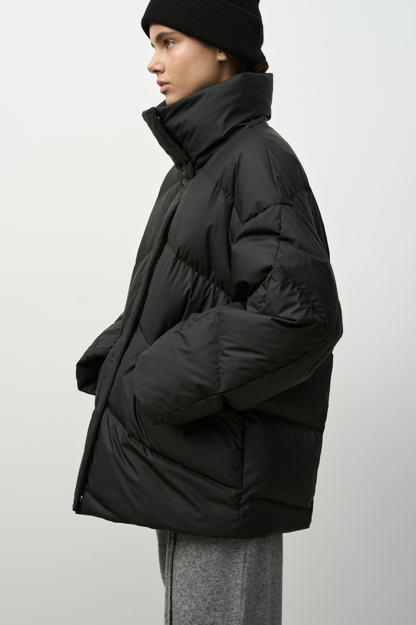 Объемный стеганый пуховик с высоким воротником-стойкой. Модель с боковыми карманами и застежкой на молнию и кнопки под планкой.