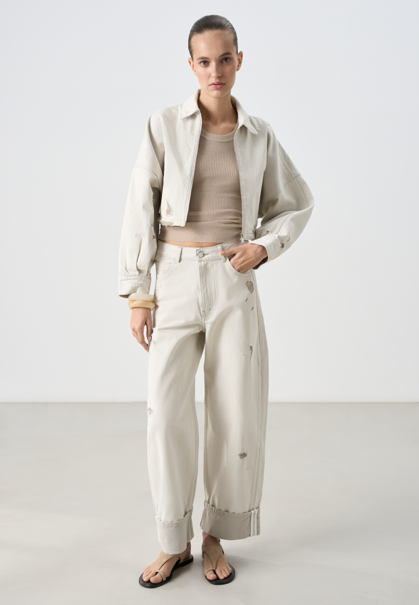 Джинсы из 100% хлопка. Модель свободного кроя с разрезами, шлевками на поясе для ремня и эффектом потертости. Застежка на молнию и пуговицу. Дополнить образ можно курткой в том же стиле.