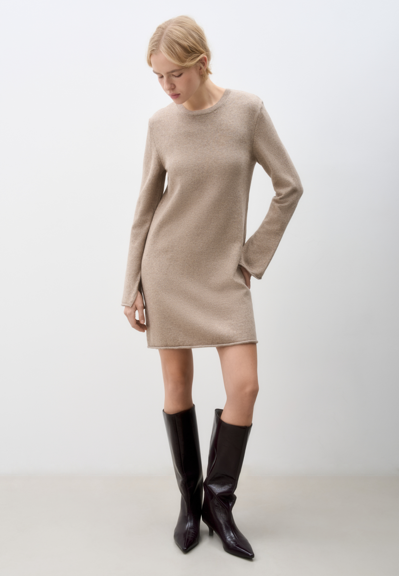 Трикотажное платье длины мини из шерсти с добавлением кашемира. Модель свободного силуэта с длинными рукавами, круглым вырезом горловины и валиком по низу изделия.