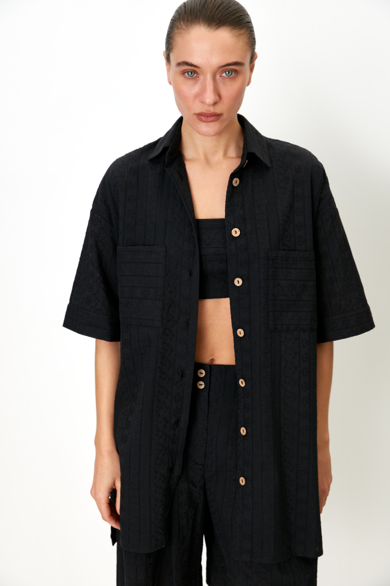 Рубашка из 100% хлопка. Модель прямого кроя, с отложным воротником и короткими рукавами. Застёгивается на пуговицы по всей длине. На груди расположены два накладных кармана. Ткань имеет текстурированную поверхность с вертикальными полосами и вышитым узором.<br />
