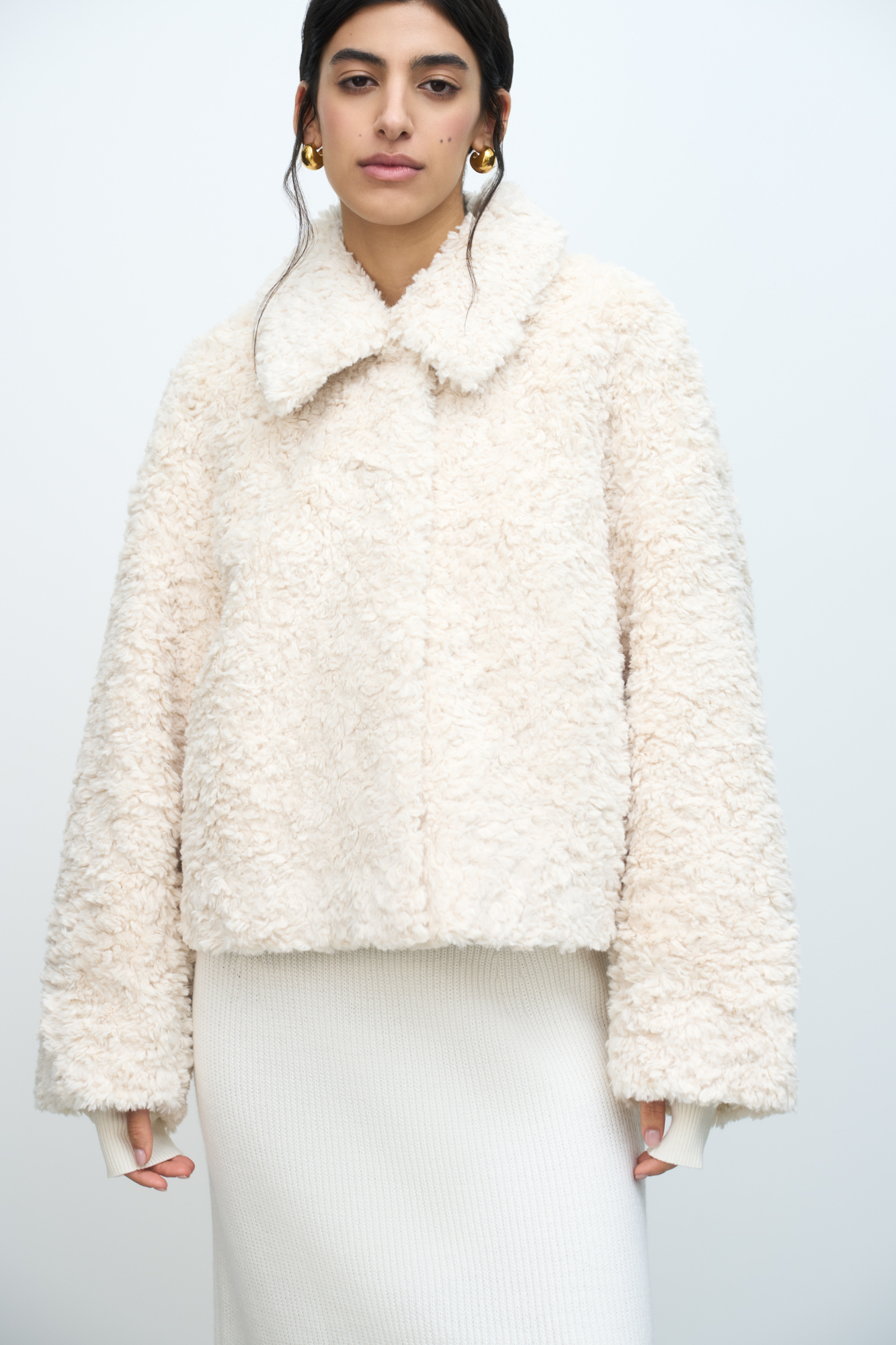 Короткая шуба из искусственного меха с отложным воротом. Застежка на кнопки под планкой. Длинные рукава с трикотажными митенками.