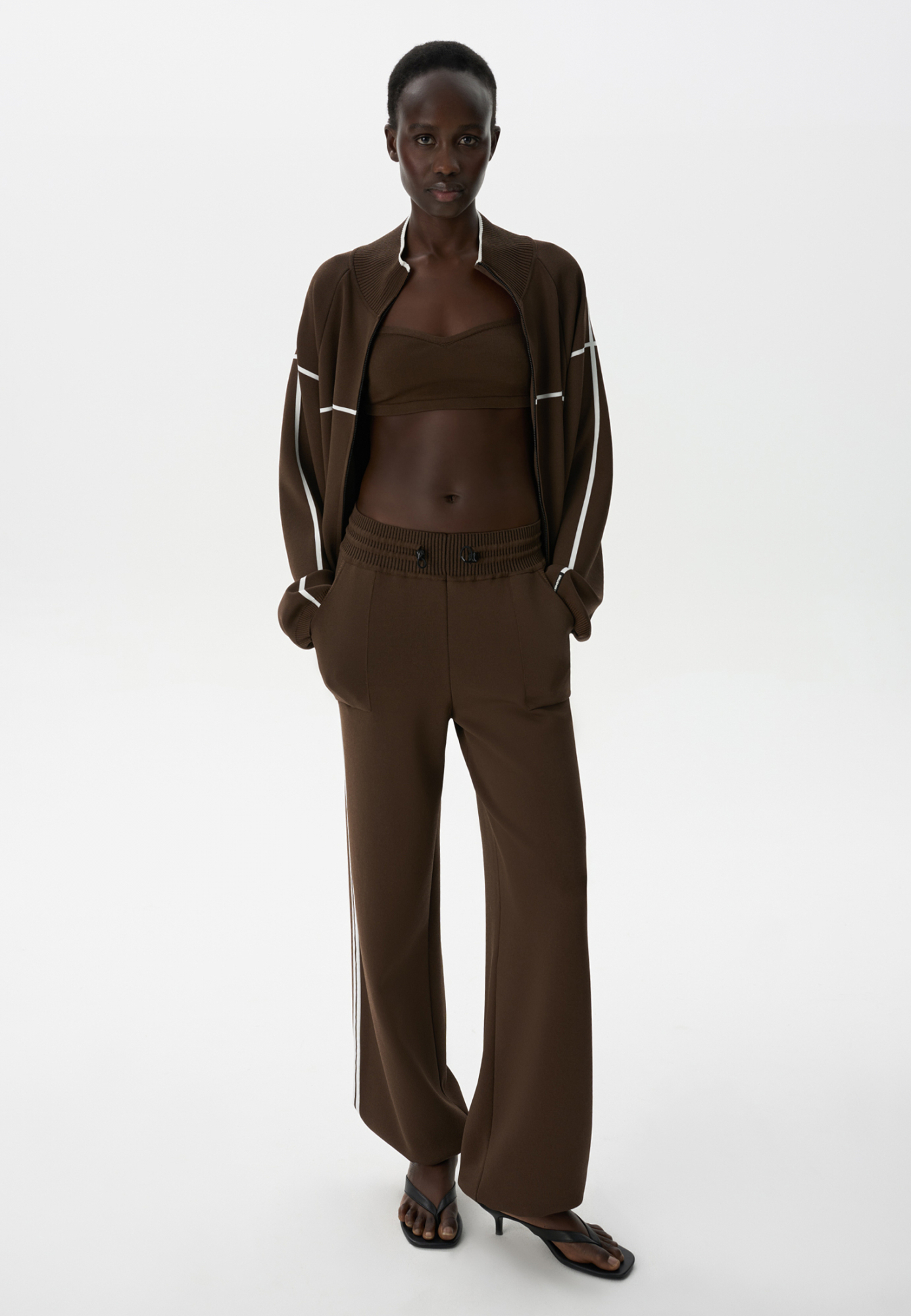 Спортивные брюки из вискозы с лампасами. Модель прямого кроя с боковыми карманами, широким поясом в рубчик и кулиской. Манжеты изделия на кулиске.