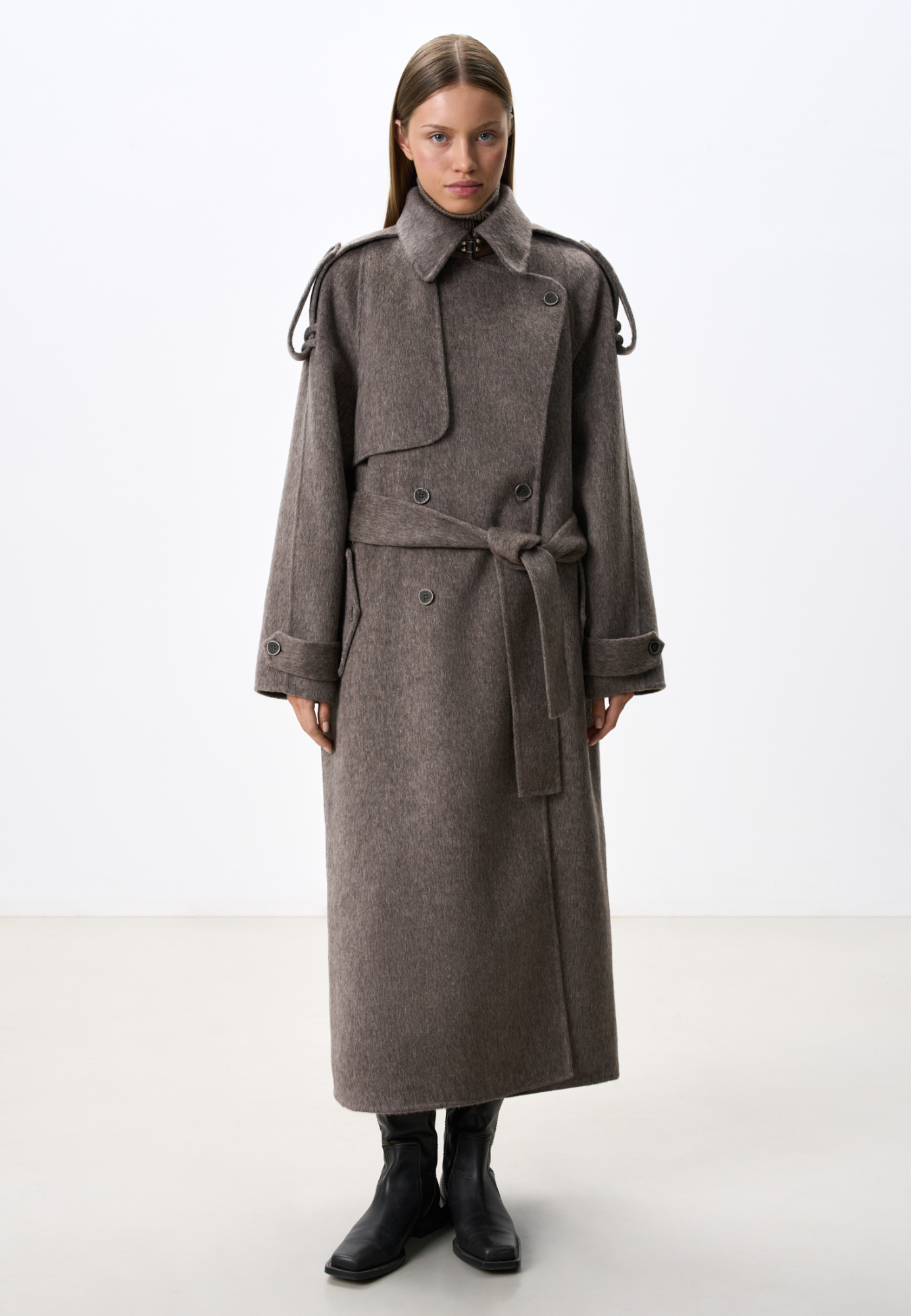 Длинное двубортное шерстяное пальто с добавлением верблюжьей шерсти. Модель прямого свободного силуэта с отложным воротником и боковыми карманами. Изделие декорировано отлетной кокеткой и широкими лацканами на плечах. На талии расположены шлевки, через которые продевается пояс, выполненный из того же материала, что и пальто. Без подкладки. 