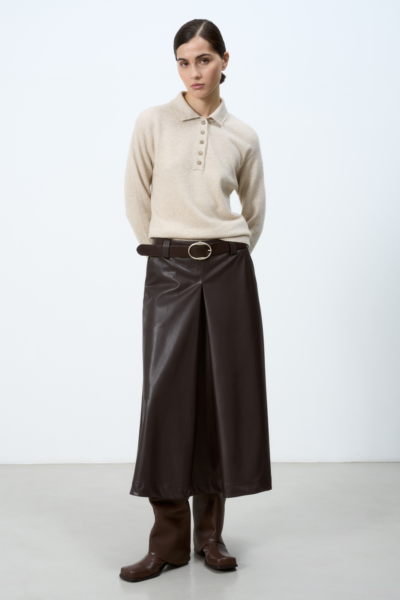 Юбка из экокожи длины миди со встречными складками, карманами и шлевками на поясе для ремня. Застежка на боковую молнию. Изделие без подкладки.