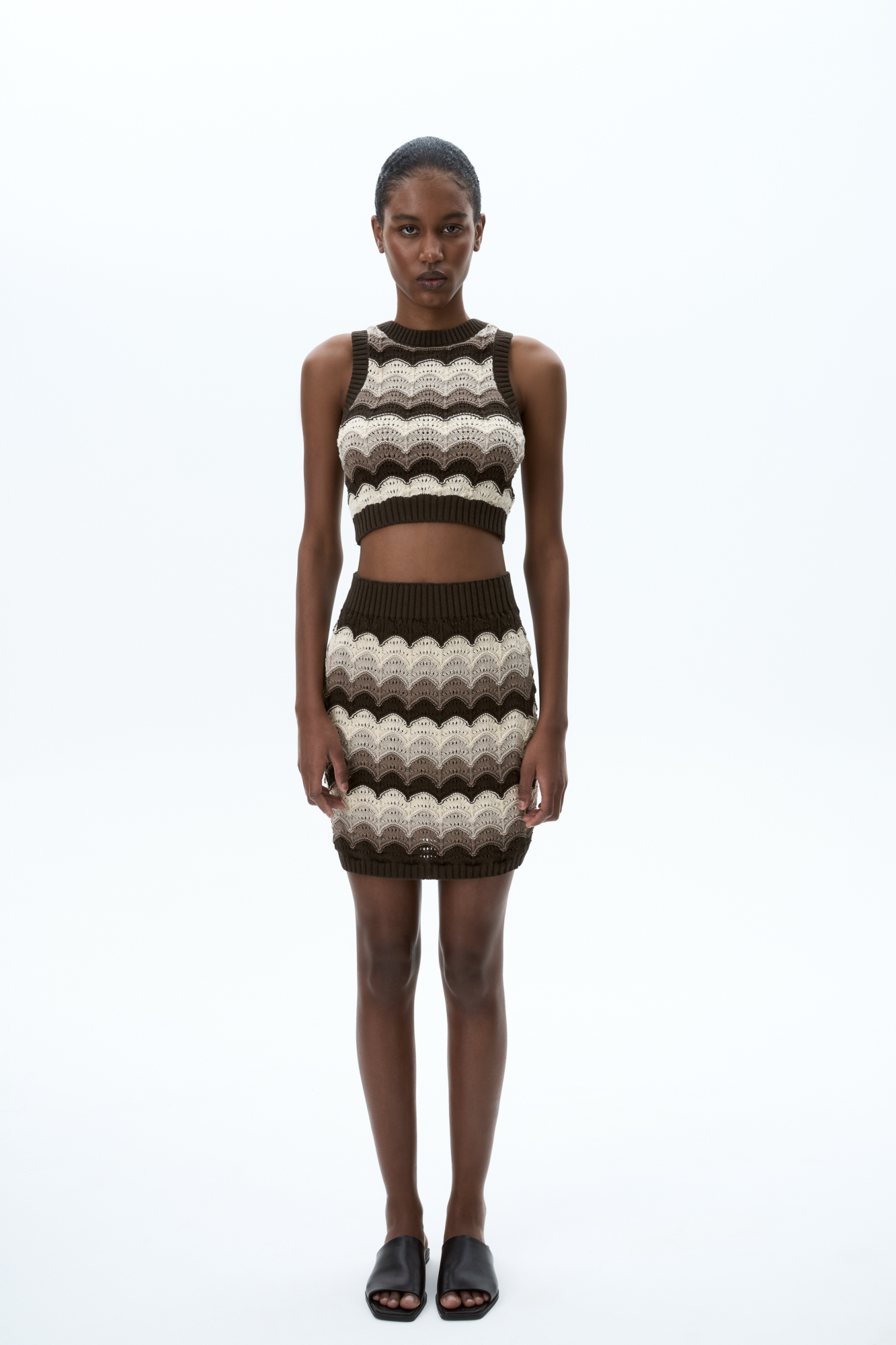 Трикотажная юбка длины мини из хлопка с добавлением эластана. Модель по фигуре, с эластичным поясом в рубчик. Изделие выполнено фактурной вязкой с волнистым узором.