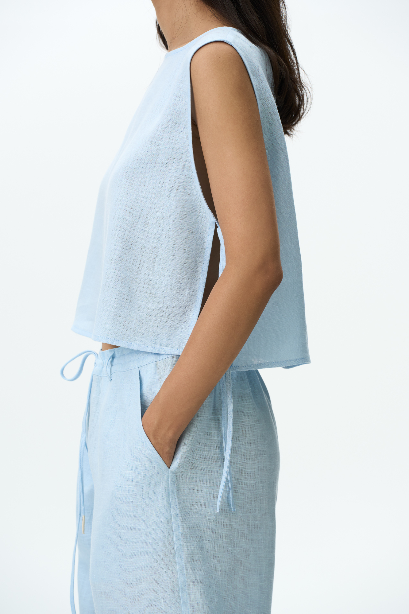 Укороченный топ из 100% льна. Модель свободного кроя, без рукавов, с круглым вырезом горловины. Изделие фиксируется завязками по бокам.