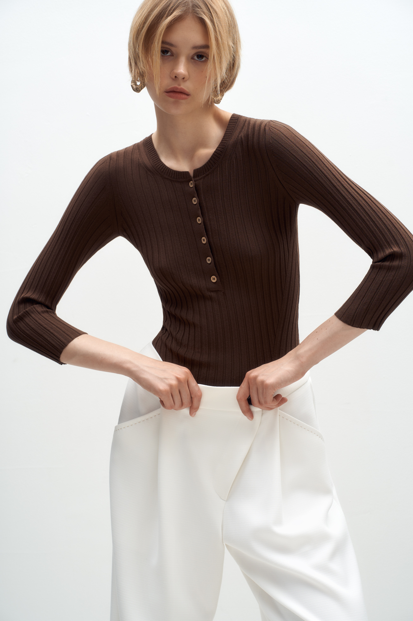 Трикотажный топ из вискозы в широкий рубчик. Модель с рукавами 3/4 и вырезом горловины с планкой на пуговицах, создающим V-образный вырез.