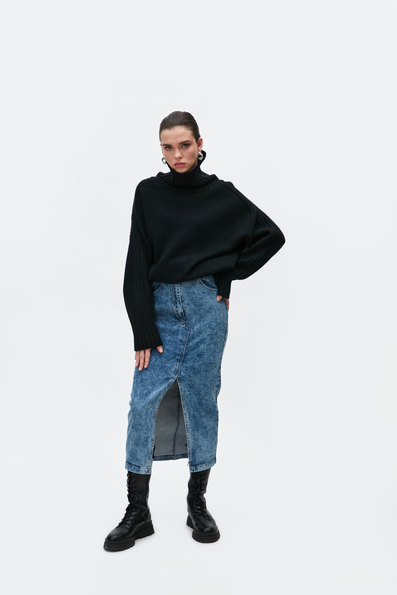 Джиносовая юбка длины миди из хлопка. Модель прямого кроя с разрезом спереди, патами на поясе для ремня и карманами. Застежка на молнию и пуговицу. 