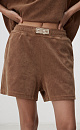 Шорты из махрового трикотажа. Модель свободного силуэта с боковыми карманами и брендированным ярлыком. Эластичный пояс на резинке в рубчик. Дополнить образ можно футболкой в таком же стиле.