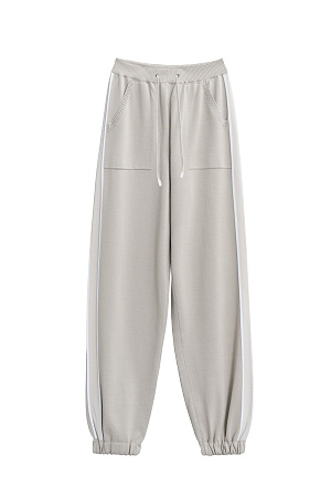 бежевый Трикотажные брюки-джоггеры из вискозы. Модель выполнена в спортивном стиле, с эластичным поясом со шнурком, боковыми карманами и манжетами на резинке. Изделие декорировано широкими лампасами контрастного цвета. 