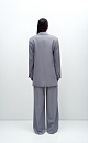 Классический костюм, состоящий из однобортного жакета и брюк палаццо. Жакет прямого кроя судлиненной спинкой, лацканами и двумя прорезными карманами с клапанами. Брюки прямого кроя с боковыми карманами и застежкой на молнию.