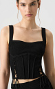 Трикотажный топ из вискозы. Модель приталенного силуэта, без рукавов, на широких бретельках, с вывязанным лифом, симметричными разрезами по бокам и шнуровкой. Дополнить образ можно юбкой в таком же стиле.
