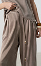 Брюки из купры. Модель свободного кроя, со шлевками на поясе для ремня, двумя боковыми карманами и карманом сзади.&nbsp;&nbsp;Застежка на молнию и пуговицу. Изделие декорировано тонким шнурком с бусинами. 
