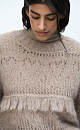 Ажурный джемпер с вывязанным узором и бахромой. Модель свободного силуэта со спущенной линией плеч и круглым вырезом горловины. Края изделия выполнены в рубчик. 