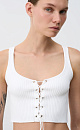 Короткий трикотажный топ из вискозы. Модель приталенного силуэта, без рукавов, на широких бретельках, с люверсами и шнуровкой на груди. Дополнить образ можно юбкой в таком же стиле.