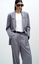 Классический костюм, состоящий из однобортного жакета и брюк палаццо. Жакет прямого кроя судлиненной спинкой, лацканами и двумя прорезными карманами с клапанами. Брюки прямого кроя с боковыми карманами и застежкой на молнию.