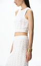 Трикотажный ажурный топ из хлопка с добавлением эластана. Модель приталенного силуэта, без рукавов, с неглубоким круглым вырезом горловины. Изделие выполнено объемным вязанием с волнистым узором и краями в рубчик. 