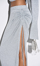 Трикотажная юбка длины макси из вискозы с люрексом. Модель облегающего силуэта, с эластичным поясом в рубчик и разрезом от бедра с кулиской. Дополнить образ можно топом в таком же стиле.