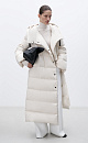 Длинный стеганый пуховик с косой застежкой на кнопки. Модель с ассиметричным низом, боковыми карманами и капюшоном. В комплекте пояс в тон.