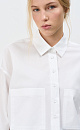 Укороченная рубашка с накладными карманами. Модель свободного силуэта со спущенной линией плеча. Застежка на пуговицы.
