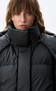 Пуховик с двумя накладными карманами, воротником-стойкой и капюшоном. Застежка на молнию под планкой. Низ изделия выполнен на регулируемой кулиске. На подкладке.