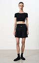 Трикотажная юбка длины мини в теннисном стиле. Модель с широким эластичным поясом в рубчик. Изделие декорировано брендированным ярлыком.