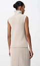Трикотажный жилет из шерсти с добавлением акрила. Модель прямого силуэта, без рукавов, с декоративными сбавками на груди и высоким воротником с валиком. Дополнить образ можно юбкой в таком же стиле.