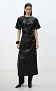 Длинное платье из экокожи. Модель свободного силуэта с коротким рукавом и круглым вырезом горловины. Изделие декорировано драпировкой и разрезом сбоку.