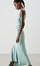 Атласное платье длины макси. Модель приталенного силуэта, с круглым вырезом горловины, без рукавов. Модель декорирована асимметричной юбкой и драпировкой на талии.