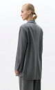 Классический жакет с накладными карманами, подплечниками, разрезами по бокам и удлиненной спинкой. Длинные рукава на манжетах без пуговиц. Застежка на пуговицу.