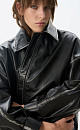 Куртка из рельефной экокожи. Модель прямого кроя, со спущенной линией плеч, отложным воротником, двумя карманами и регулируемой кулиской по низу. Застежка на молнию под планкой с кнопками. Изделие декорировано имитацией потертостей по швам и логотипом бренда на спине. На подкладке. 